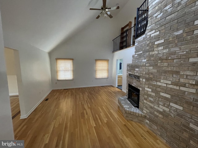 unfurnished living room with high vaulted ceiling, baseboards, a ceiling fan, and light wood-style floors