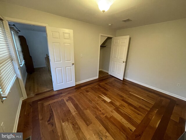unfurnished bedroom with baseboards, a closet, visible vents, and wood finished floors