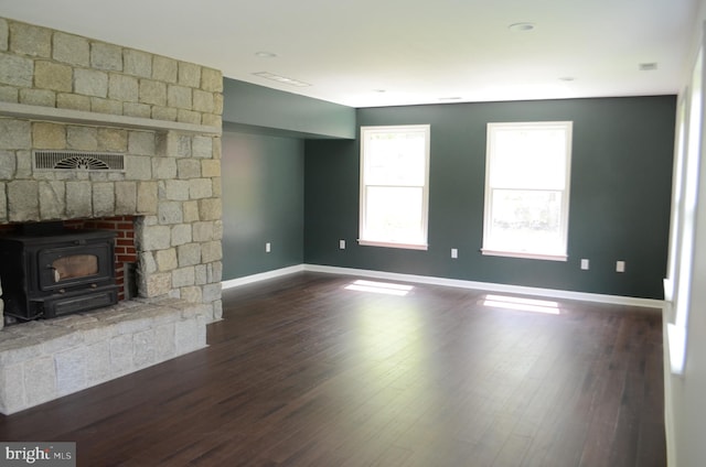 unfurnished living room with a wood stove and dark wood-type flooring