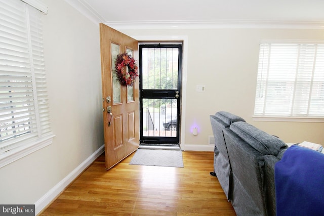 entryway with light wood-type flooring and crown molding