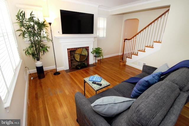 living room featuring wood-type flooring, a fireplace, and crown molding