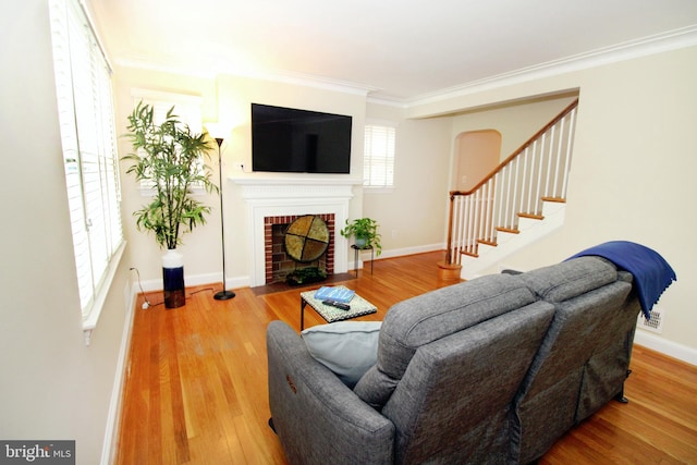 living room featuring hardwood / wood-style flooring, crown molding, and a brick fireplace