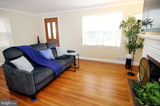 living room featuring a brick fireplace, crown molding, and light hardwood / wood-style floors