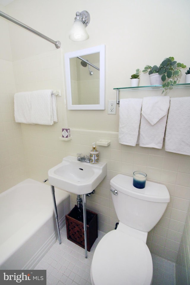 bathroom featuring tile walls, tiled shower / bath combo, toilet, and tile patterned flooring