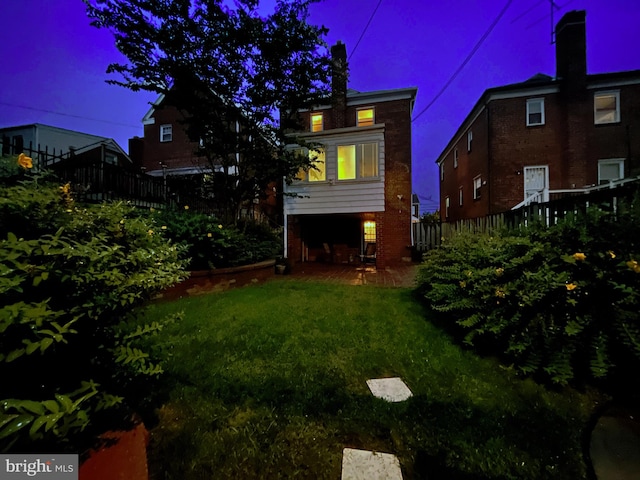 back house at dusk featuring a yard