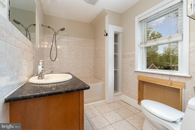 full bathroom with tile walls, tiled shower / bath combo, tile patterned floors, vanity, and toilet