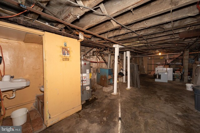 basement with gas water heater, sink, and washing machine and dryer