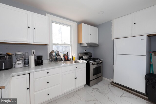 kitchen featuring white refrigerator, gas stove, sink, and white cabinets