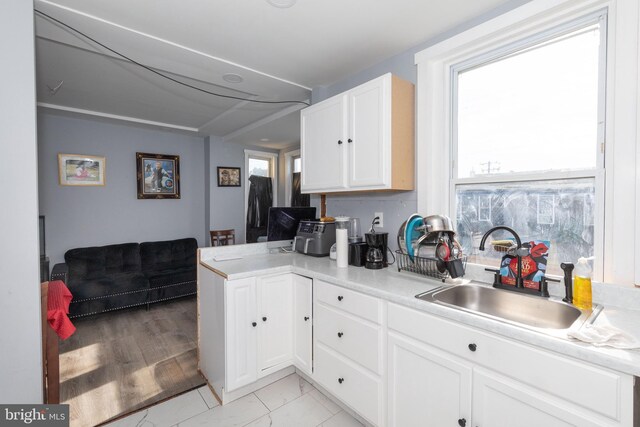 kitchen with white cabinetry, kitchen peninsula, and sink