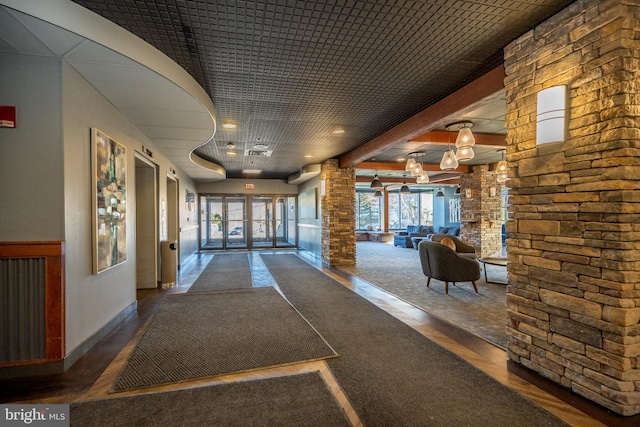 hallway with dark wood-type flooring, an inviting chandelier, and ornate columns