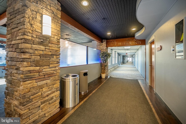 hallway with dark carpet and beamed ceiling