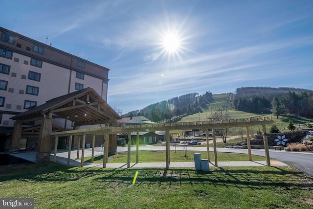 view of community featuring a water view, a lawn, and a pergola