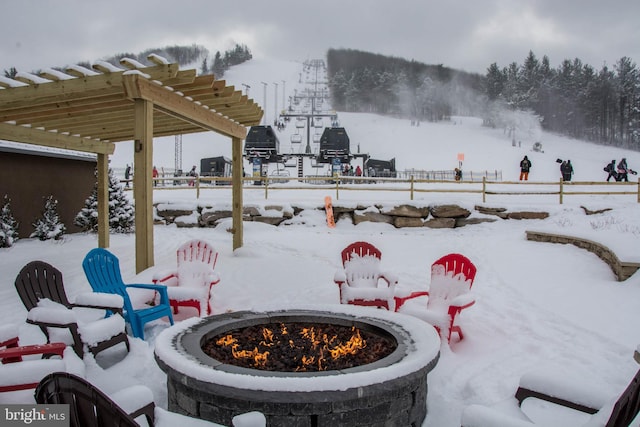 snow covered patio with a pergola and a fire pit