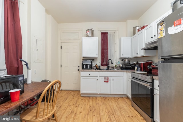 kitchen with white cabinets, appliances with stainless steel finishes, light hardwood / wood-style floors, and sink