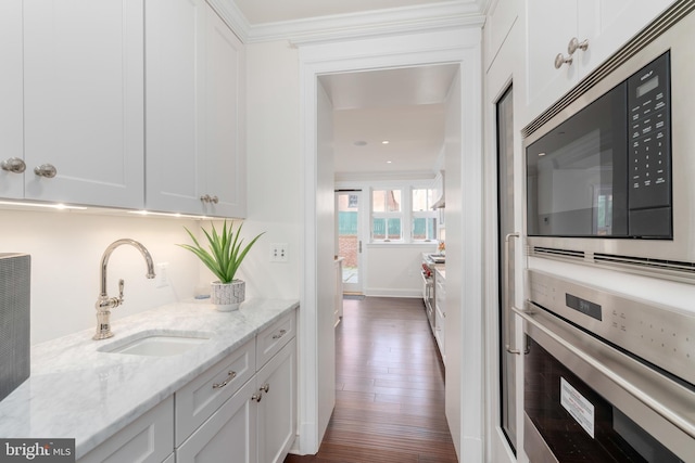 kitchen featuring appliances with stainless steel finishes, light stone counters, white cabinets, dark hardwood / wood-style floors, and sink