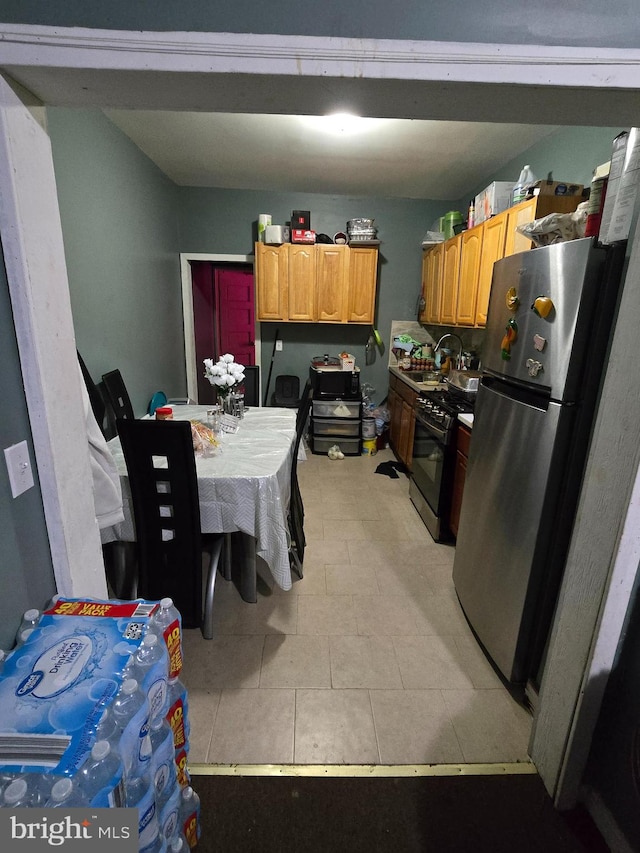 kitchen with appliances with stainless steel finishes, sink, and light tile patterned floors