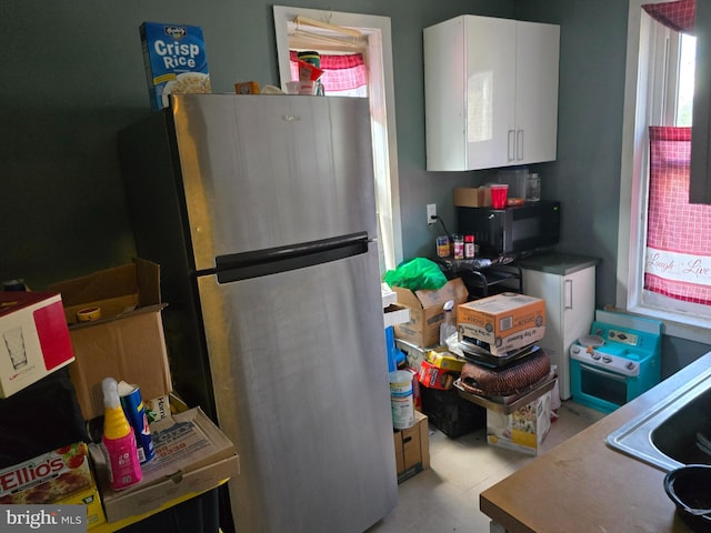 kitchen with sink, white cabinetry, and stainless steel refrigerator