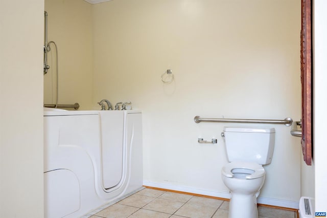 bathroom featuring tile patterned flooring, toilet, a baseboard heating unit, and washer / dryer