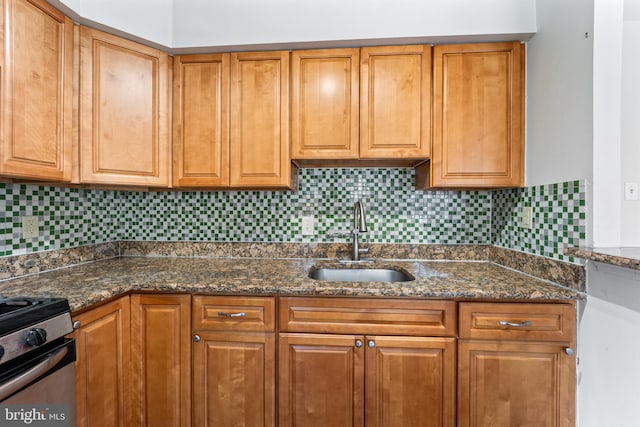 kitchen with dark stone counters, stainless steel electric range oven, sink, and decorative backsplash