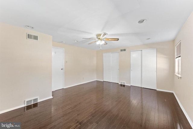 unfurnished bedroom with two closets, ceiling fan, and dark wood-type flooring