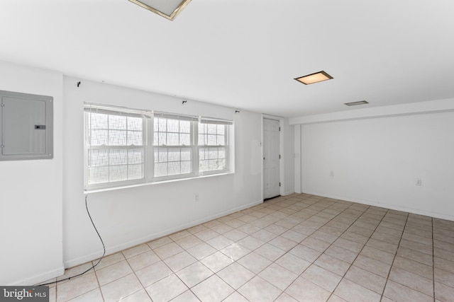 empty room with light tile patterned floors, electric panel, and a healthy amount of sunlight