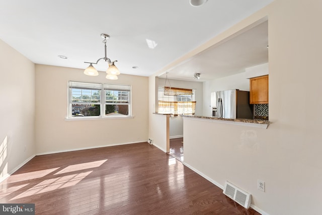 unfurnished living room with a notable chandelier and dark wood-type flooring