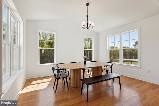 dining area with a notable chandelier, lofted ceiling, hardwood / wood-style floors, and a wealth of natural light