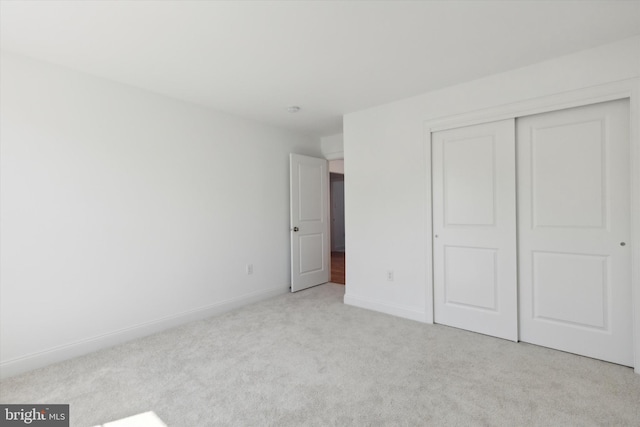 unfurnished bedroom featuring a closet and light colored carpet