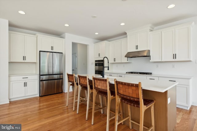 kitchen with stainless steel appliances, white cabinets, and a kitchen island with sink