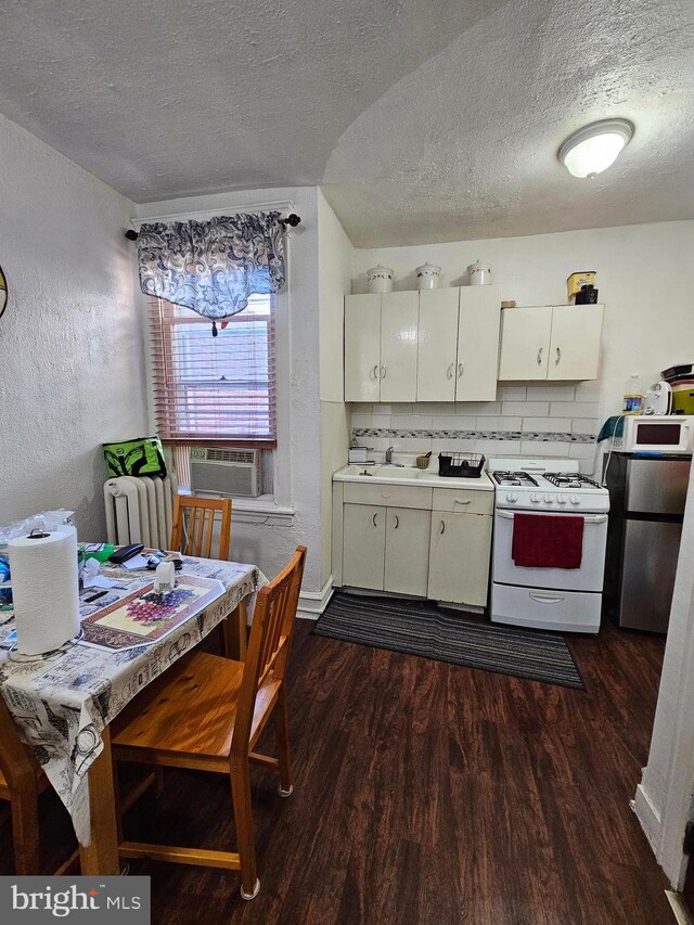 kitchen featuring a textured ceiling, dark hardwood / wood-style flooring, white appliances, and tasteful backsplash