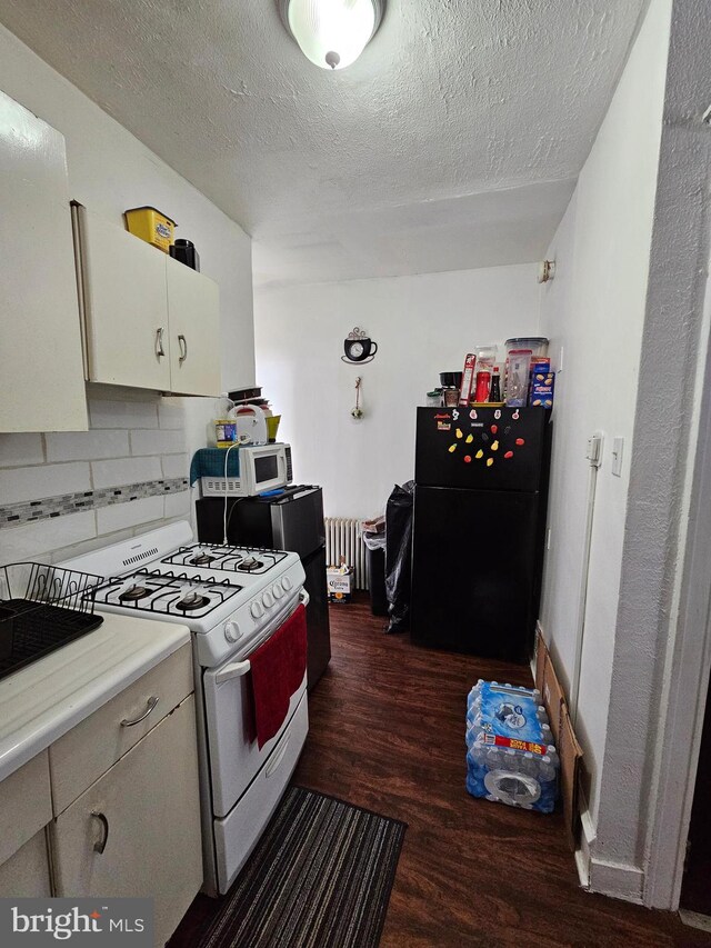 kitchen with tasteful backsplash, white appliances, dark hardwood / wood-style flooring, a textured ceiling, and radiator