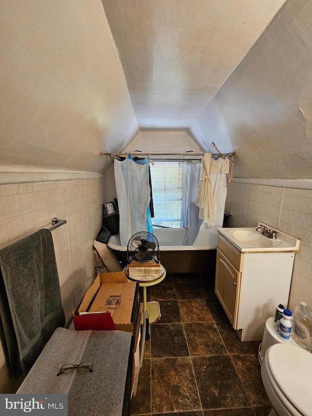 full bathroom featuring tile walls, lofted ceiling, and toilet