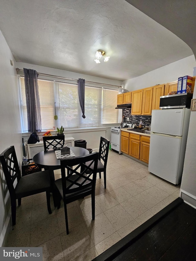 kitchen featuring white appliances, a textured ceiling, and backsplash