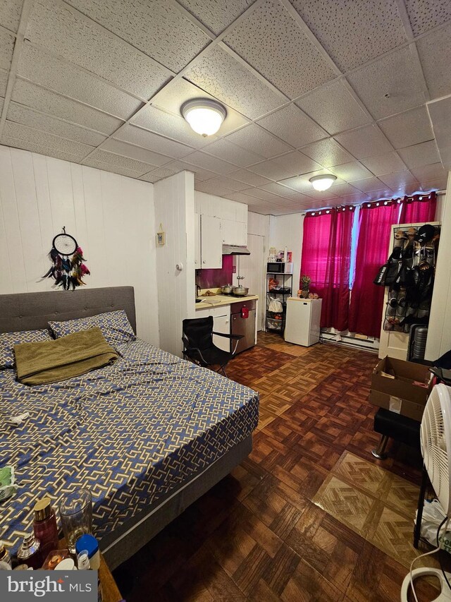 bedroom featuring a paneled ceiling, a baseboard radiator, and dark parquet flooring