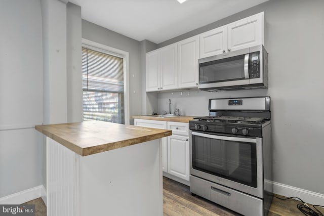 kitchen with light wood-type flooring, white cabinets, stainless steel appliances, and sink