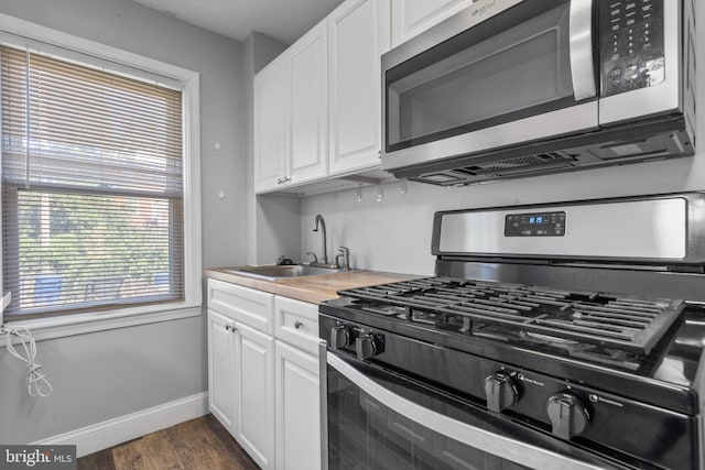 kitchen featuring dark wood-type flooring, white cabinets, appliances with stainless steel finishes, and sink