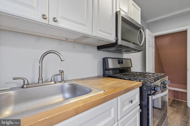 kitchen featuring wooden counters, sink, dark wood-type flooring, appliances with stainless steel finishes, and white cabinets