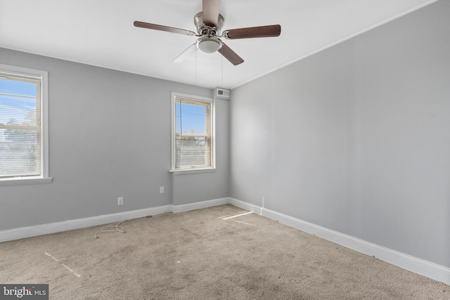 spare room featuring a wealth of natural light, ceiling fan, and light carpet