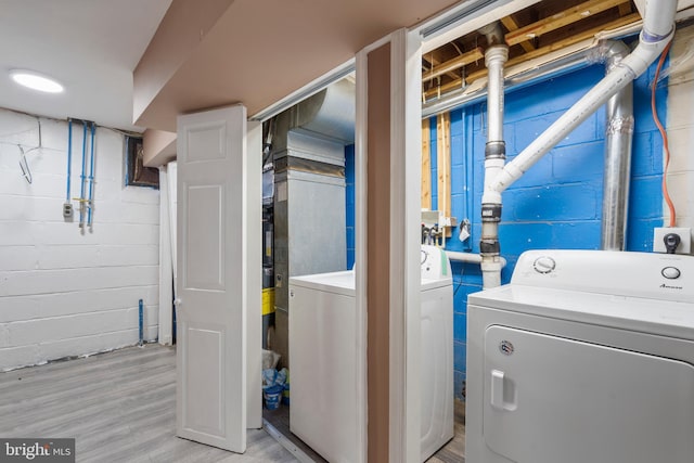 clothes washing area with light hardwood / wood-style floors and washer and clothes dryer