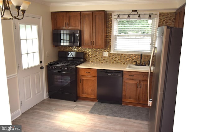 kitchen featuring ornamental molding, black appliances, sink, and light hardwood / wood-style floors