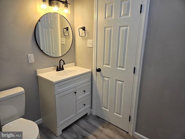 bathroom with vanity, toilet, and hardwood / wood-style floors