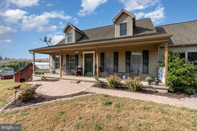 cape cod-style house featuring a porch and a front lawn