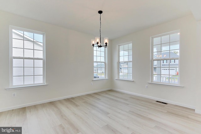 unfurnished room featuring a notable chandelier and light hardwood / wood-style floors