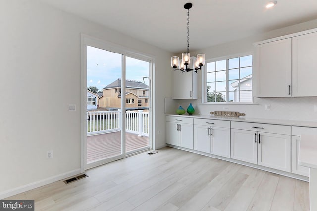 kitchen featuring hanging light fixtures, white cabinetry, a chandelier, and light hardwood / wood-style flooring