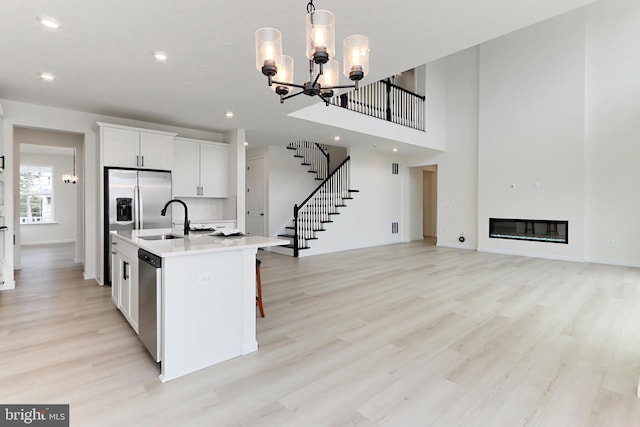 kitchen featuring pendant lighting, a center island with sink, white cabinetry, a notable chandelier, and light hardwood / wood-style floors