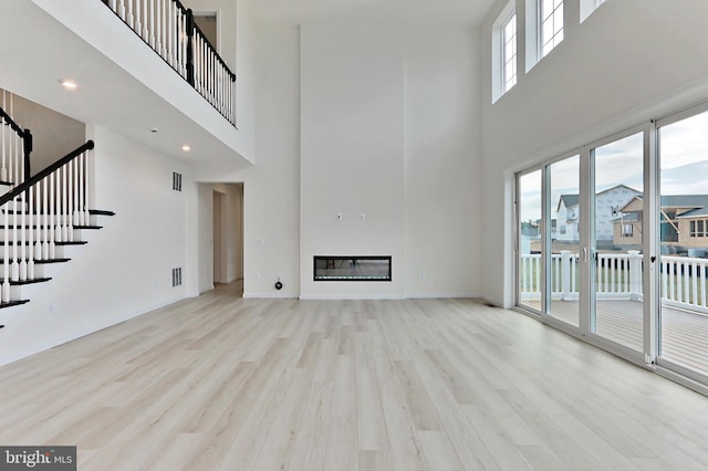 unfurnished living room featuring light hardwood / wood-style flooring and a high ceiling