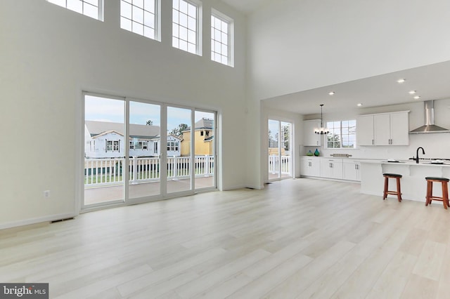 living room with light hardwood / wood-style floors, a towering ceiling, a chandelier, and plenty of natural light