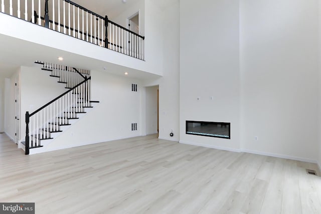 unfurnished living room featuring light hardwood / wood-style flooring and a high ceiling