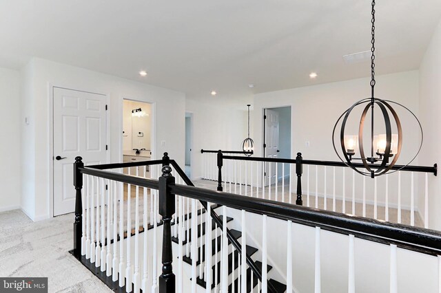 corridor featuring light carpet and a notable chandelier