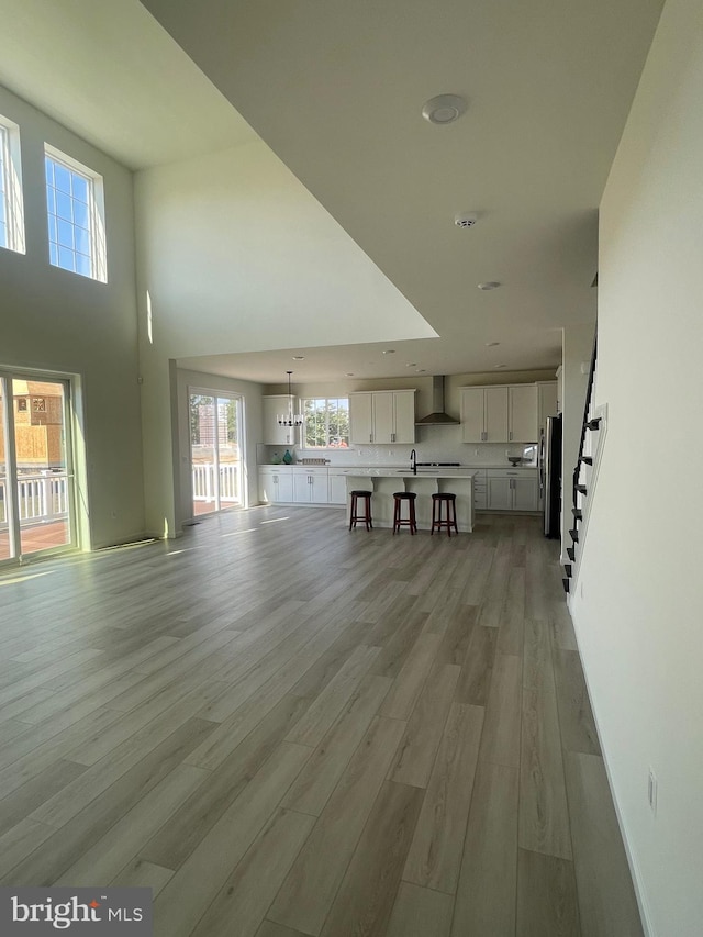 unfurnished living room with a high ceiling, light hardwood / wood-style floors, and sink